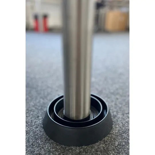 Das Bild zeigt ein Metallmöbelbein, das in einer schwarzen Bettwanzen-Falle auf Teppichboden platziert ist. Diese Falle verhindert, dass Bettwanzen unbemerkt Möbelstücke erklimmen können, und dient gleichzeitig als Monitoring-System. Sie ist eine einfache, diskrete und kostengünstige Methode zur Vorbeugung und Früherkennung von Bettwanzenbefällen – geeignet für Privathaushalte, Hotels, Büros und Gemeinschaftseinrichtungen.